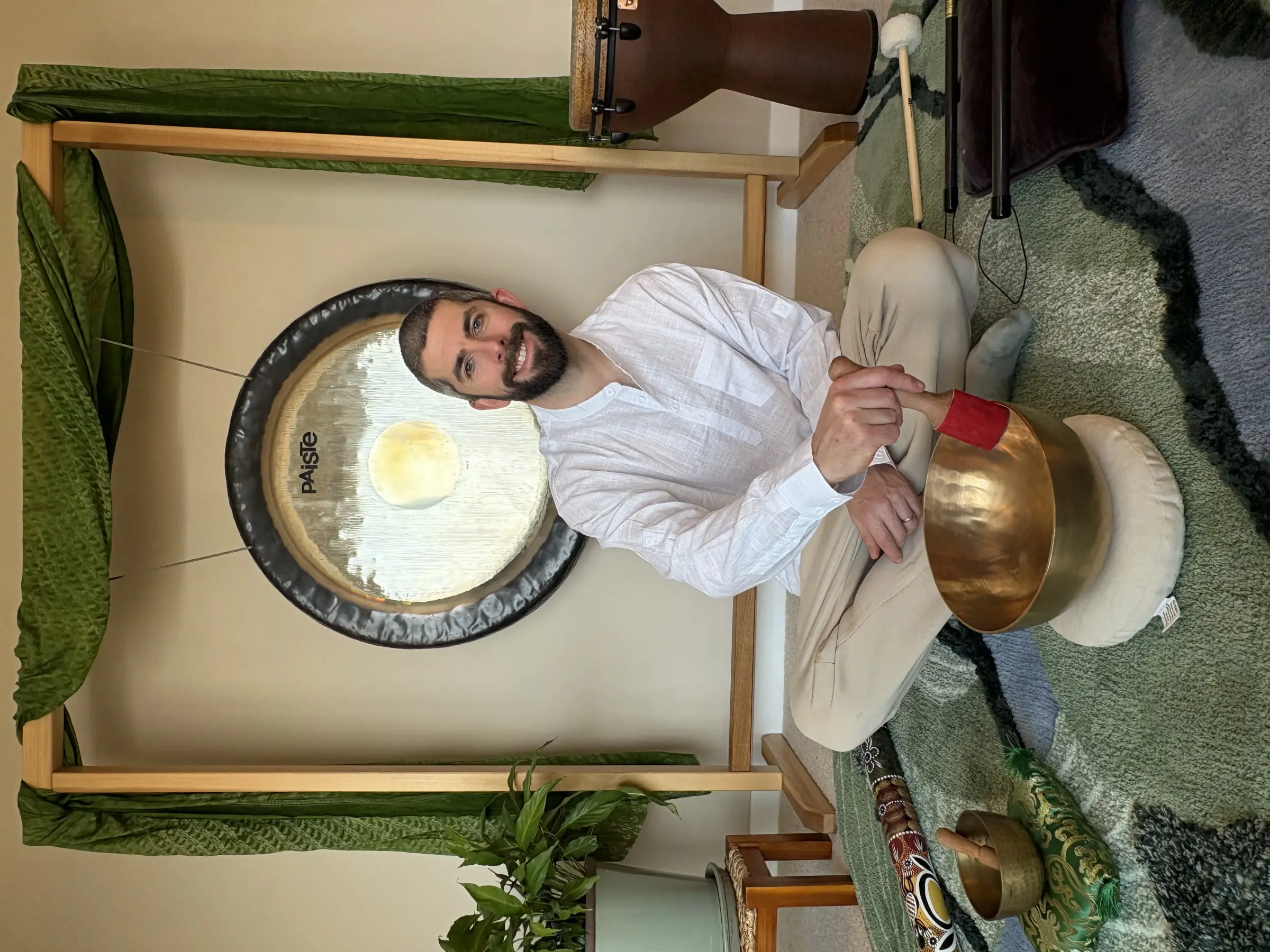 Sam seated in front of a large gong and crystal bowls